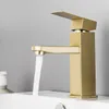 A gold-colored bathroom faucet with water running into a white sink. Podgląd zdjęcia produktu