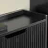 A close-up view of a black cabinet with a fluted front and a tray-like top. Náhľad obrázku produktu