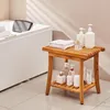 A wooden shower stool with various toiletries placed on it, next to a bathtub. Podgląd zdjęcia produktu