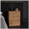 A wooden nightstand with two drawers, placed next to a bed in a bedroom. There are decorative items on top of the nightstand, including a vase with reeds and two candles. Produktbild-Vorschau