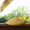 A wooden bowl filled with birdseed sits on a wooden surface, with a blurred background of greenery and flowers. Produktbild-Vorschau