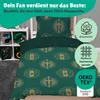 A close-up view of a green duvet cover with a gold pattern, placed on a bed. To the left, a white shelf unit holds various items, including books and decorative objects. To the right, circular badges with text and icons are overlaid on the image. Produktbild-Vorschau