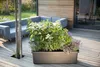 A rectangular planter filled with plants sits on a wooden deck next to a modern outdoor sofa. Náhled obrázku produktu