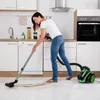 A woman is vacuuming a kitchen floor. Produktbild-Vorschau