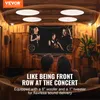 A couple is relaxing on a couch, watching a screen, with ceiling speakers and sound waves depicted. Voir les images du produit