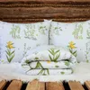 A folded duvet and two pillows with a floral pattern are displayed on a white fluffy rug, placed on a wooden surface, with a wooden wall in the background. Produktbild-Vorschau