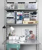 A desk with shelves above, filled with storage boxes and art supplies. Produktbild-Vorschau