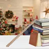 A wooden advent calendar shaped like stairs with numbers 1-24 is placed on a table in front of a blurred Christmas-decorated room. A stack of books is next to the calendar. Produktbild-Vorschau