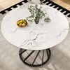 A round marble-top dining table with a black metal base, set on a rug. Produktbild-Vorschau
