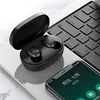 A pair of black wireless earbuds in their charging case, placed next to a laptop keyboard and a smartphone. Produktbild-Vorschau