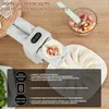 A close-up of an automatic dumpling maker with filling ingredients in a bowl in the background. Produktbild-Vorschau