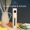 A white oil sprayer is placed on a wooden table with kitchen utensils and herbs in the background. Anteprima dell’immagine prodotto