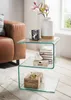 A glass side table next to a leather sofa, decorated with a vase, flowers, a mug, books, and decorative boxes. Voir les images du produit