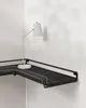 A white desk lamp is on a black L-shaped shelf mounted on a white wall. Náhled obrázku produktu