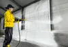A person is using a Kärcher foam lance to spray a wall in what appears to be an industrial or agricultural building. Produktbild-Vorschau