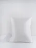 A white pillow on a white surface with a small white box to the left. Podgląd zdjęcia produktu