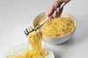 A hand is using a spaghetti server to serve pasta from a bowl onto a plate. Podgląd zdjęcia produktu