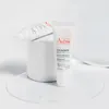 Two tubes of Avène Cicalfate lip balm are displayed on a white surface with a white cylindrical object behind them. Podgląd zdjęcia produktu