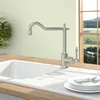 A kitchen sink with a faucet and plates of cutlery, with a window showing a landscape in the background. Produktbild-Vorschau