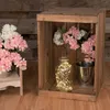 A rustic wooden crate filled with decorative items, including flowers and a string of lights in a glass jar. Produktbild-Vorschau
