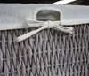 A close-up view of the top of a woven basket with a fabric lid tied with a bow. Náhľad obrázku produktu