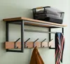 A wall-mounted coat rack with a shelf and hooks, holding a scarf and a coat. A basket with folded towels is on the shelf. Produktbild-Vorschau