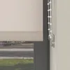 A close-up of a roller blind with a beaded pull cord and a clear plastic cord holder. Produktbild-Vorschau