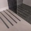 A close-up view of anti-slip strips applied to a tiled floor in a bathroom, leading towards a shower enclosure. Náhľad obrázku produktu