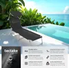 A black sun lounger is placed on a patio next to an infinity pool with a tropical background. Náhled obrázku produktu