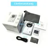 A white digital camera and its accessories are laid out on a white background, next to its packaging. Produktbild-Vorschau