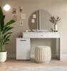 A white dressing table with a round mirror, a stool, and a plant in a pot, set in a room with light beige walls and a wooden floor. Produktbild-Vorschau