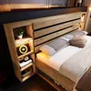 A modern wooden bed frame with integrated shelving and lighting. Náhled obrázku produktu