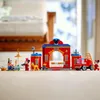 A LEGO set of Mickey and Friends fire station and fire truck, with figures and a dog, displayed on a wooden floor. Produktbild-Vorschau