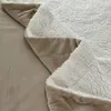 A close-up view of a folded beige sherpa fleece blanket. Náhled obrázku produktu
