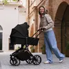 A woman pushing a stroller down a cobblestone street. Voir les images du produit