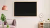 A living room scene with a chalkboard mounted on the wall above a cabinet and next to a clock. Produktbild-Vorschau