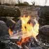 A disposable grill is placed over a campfire, surrounded by rocks and logs. Produktbild-Vorschau