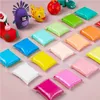A collection of colorful modeling clay packs arranged on a pink surface, with some small clay figures in the background. Náhled obrázku produktu