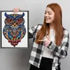 A young woman is holding up a framed puzzle of an owl. Náhled obrázku produktu