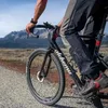 A person riding a bicycle on a gravel road with mountains in the background. Anteprima dell’immagine prodotto