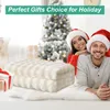 A couple in Santa hats posing in front of a Christmas tree, with a folded blanket in the foreground. Produktbild-Vorschau
