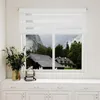 A white zebra blind is installed on a window overlooking a mountainous landscape with houses. Voir les images du produit