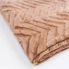 A close-up, folded view of a brown blanket with a chevron pattern. Podgląd zdjęcia produktu