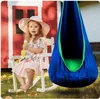 A young girl sits in a rocking chair next to a hanging chair in a backyard setting. Produktbild-Vorschau