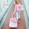 A young girl is walking down a hallway, pulling a pink unicorn-themed suitcase and wearing a matching backpack. Produktbild-Vorschau