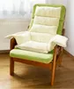 A green armchair with beige cushions sits in a room with a radiator and curtains in the background. Náhled obrázku produktu