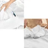 A collage showing two close-up views of white bedding. The left side shows a hand holding the corner of a duvet cover near a zipper with a brand tag. The right side shows hands tying the corner of a duvet cover with a ribbon. Podgląd zdjęcia produktu