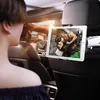 A person in the front seat of a car is looking at a tablet mounted on the back of the headrest in front of them. The tablet displays an image of a muscular man lifting weights. Anteprima dell’immagine prodotto