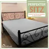A bed with a fitted sheet and a decorative headboard, with marketing text overlay. Produktbild-Vorschau