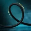 A black audio cable is bent into a loop against a dark teal and black smoky background. Náhled obrázku produktu